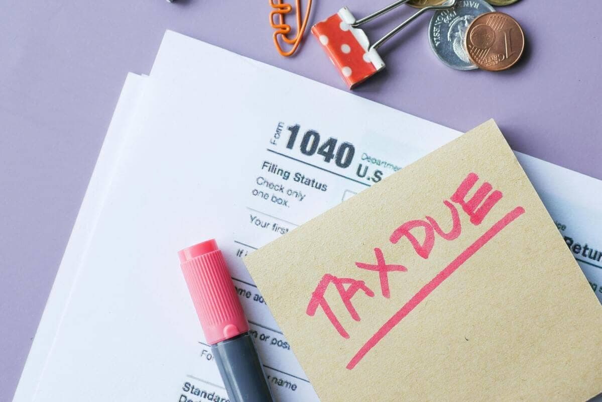 Tax forms with a 'TAX DUE' sticky note and pen