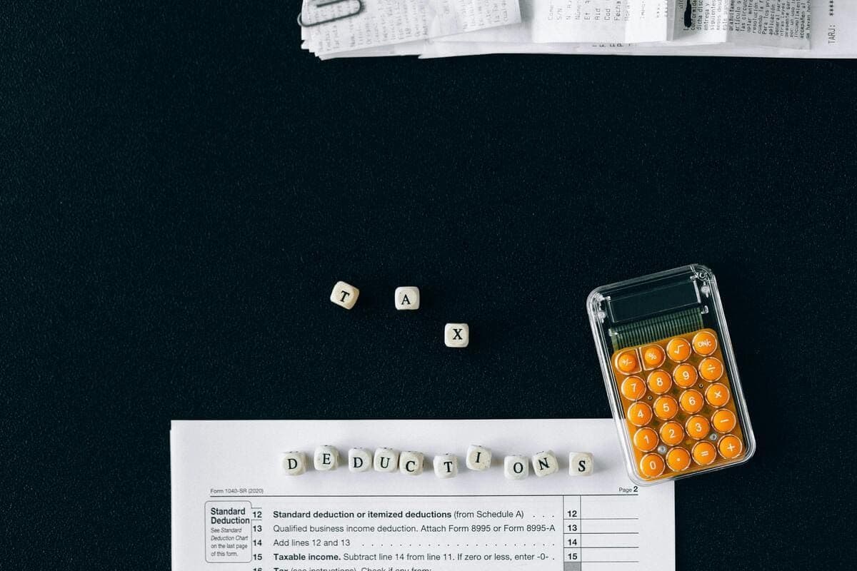 Calculator and tax forms on a dark surface, with small letter dice